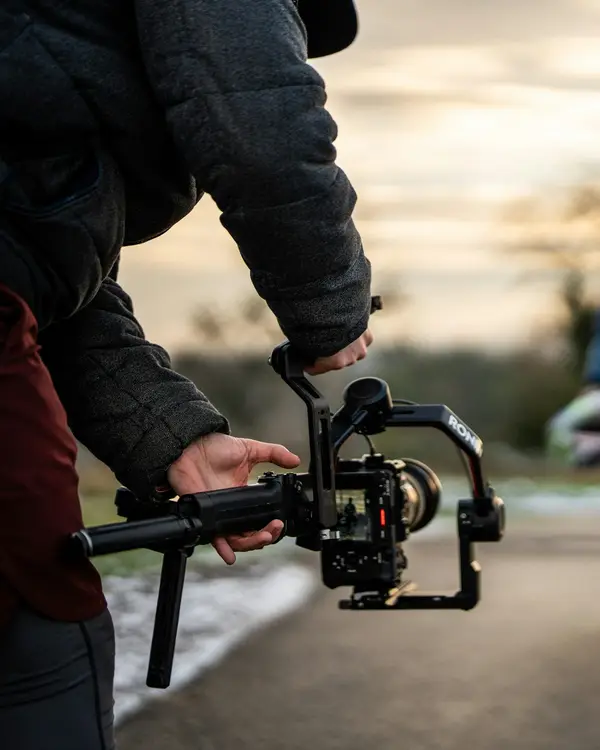 Filmemacher mit einer Kamera auf einem Hand-Gimbal, der eine Person im Freien filmt