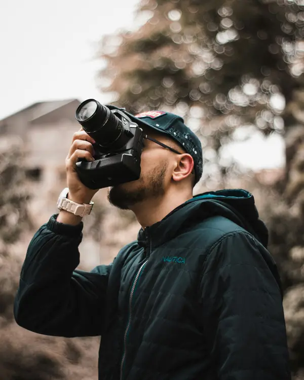 Fotograf im Freien, der mit einer DSLR und Zoomobjektiv nach oben fotografiert