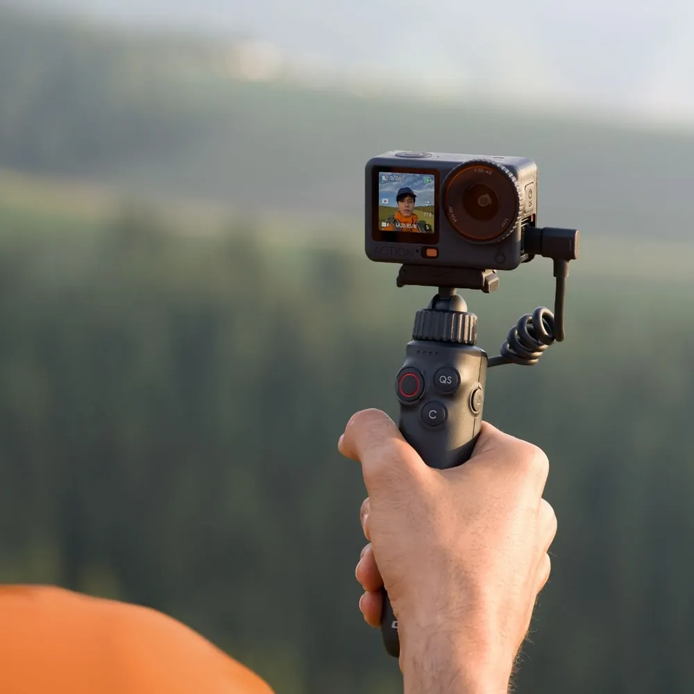 DJI Osmo Action 6 held on a grip outdoors, front screen showing the shot