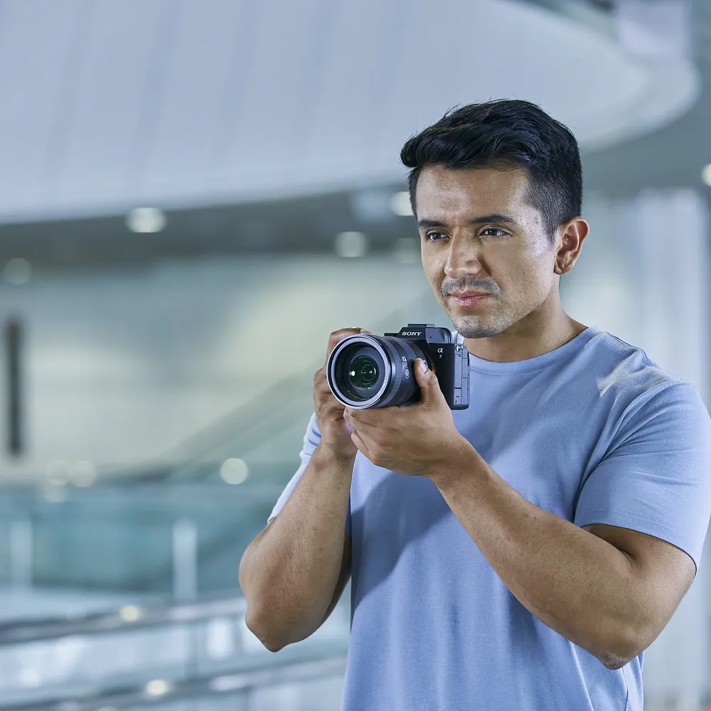 Sony Alpha 7 IV body, photographer holding the camera, official Sony image